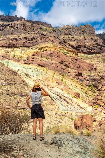 A woman with a hat at the Natural Monument Azulejos de Veneguera or Rainbow Rocks in Mogan, Gran Canaria