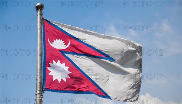 The flag of Nepal, fluttering in the wind, isolated against a blue sky