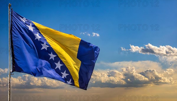 The flag of Bosnia and Herzegovina flutters in the wind, isolated against a blue sky