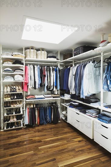 Walk-in his and hers closet with skylight window, American walnut flooring on upstairs floor inside modern cube style home, Quebec, Canada, North America