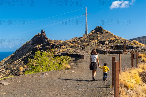 A mother and her son walking along the rock formation on the coast of Agaete, Roque Guayedra, Gran Canaria