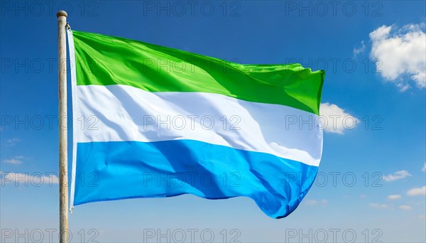 The flag of Sierra Leone, fluttering in the wind, isolated, against the blue sky