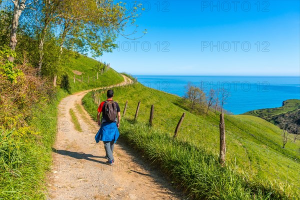 A male tourist trekking on the climb to the flysch of Zumaia, Gipuzkoa. Basque Country