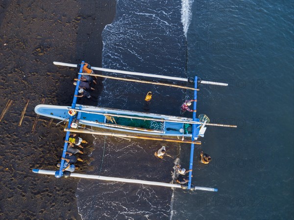 Fishermen loading fish from their outrigger boats in the morning on the black beach of Amed, Amed, Karangasem, Bali, Indonesia, Asia