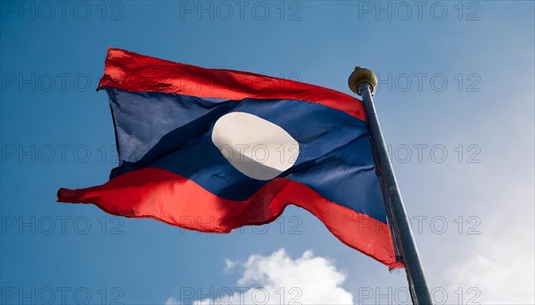 The flag of Laos flutters in the wind, isolated against a blue sky