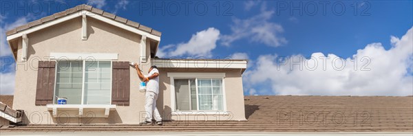 Banner of busy house painter painting the trim and shutters of A home
