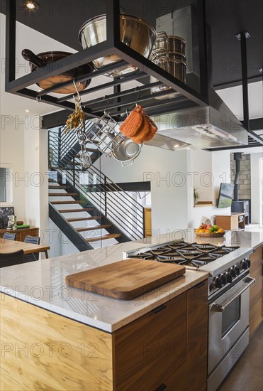 American walnut wood island with quartzite countertop and built-in gas stove in the kitchen inside modern cube style home, Quebec, Canada, North America