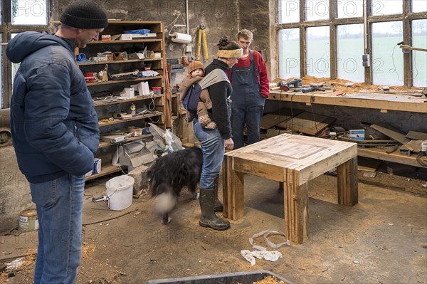 Family inspecting the table built by their son in the workshop, Mecklenburg-Vorpommern, Germany, Europe