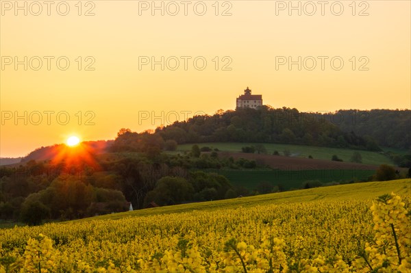 Landscape at sunrise. Beautiful morning landscape with fresh yellow rape fields in spring. Small castle in the yellow fields on a hill. Historic Ronneburg Castle in the middle of nature, Ronneburg, Hesse, Germany, Europe