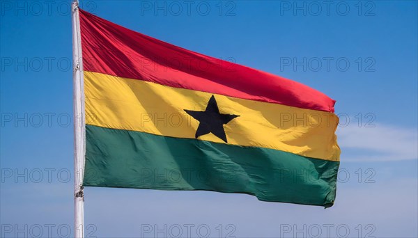 The flag of Ghana flutters in the wind, isolated against a blue sky