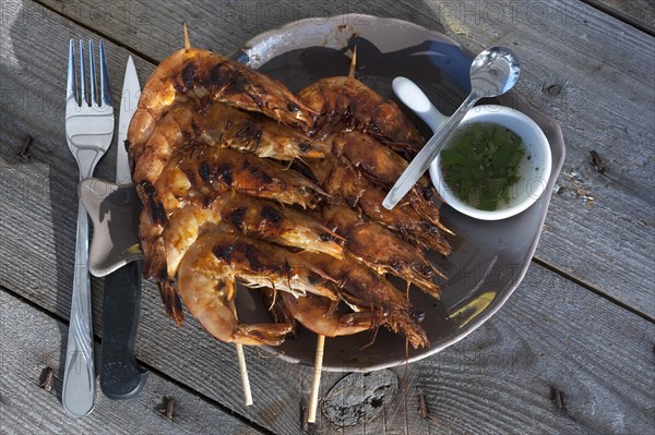 Spit-roasted prawns served on a plate at a rough wooden table, Vandee, France, Europe