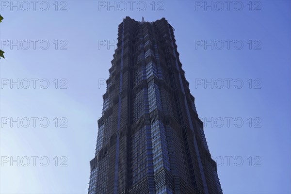 The facade of a geometrically designed skyscraper stands out against the blue sky, Shanghai, China, Asia