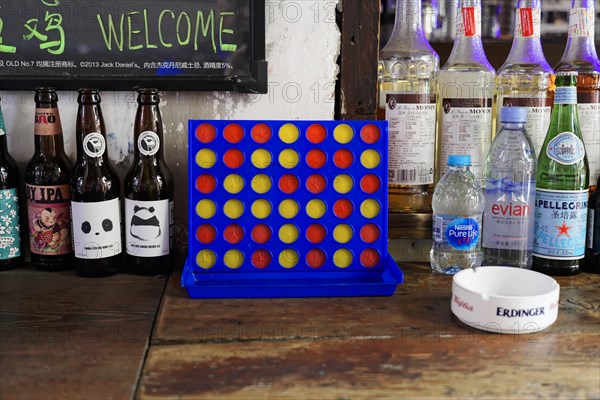 Strolling through the restored Tianzifang neighbourhood, A Connect Four game on a counter in a cafe next to various bottles of beer, Shanghai, China, Asia
