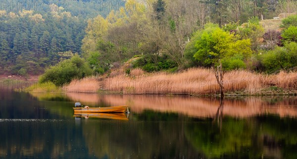 Small yellow metal fishing boat with small engine mount floating peacefully on a lake in South Korea