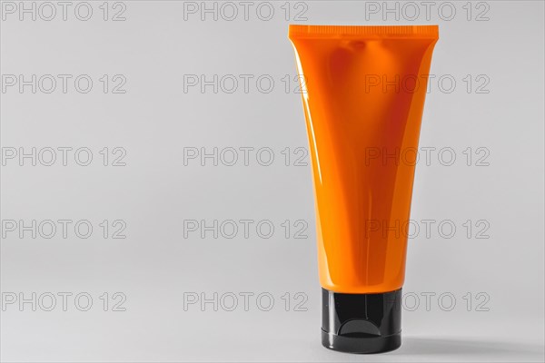 Orange sunscreen tube on white studio background with copy space. KI generiert, generiert, AI generated