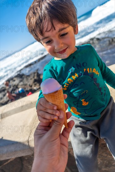 Father giving the child a delicious ice cream by the sea in summer. Family vacation concept