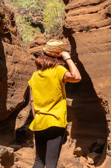 A tourist woman with hat in the limestone canyon Barranco de las Vacas in Gran Canaria, Canary Islands