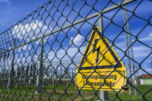 Yellow warning sign with the inscription Hochspannung Lebensgefahr! on a fence of the Avacon substation Helmstedt, Helmstedt, Lower Saxony, Germany, Europe