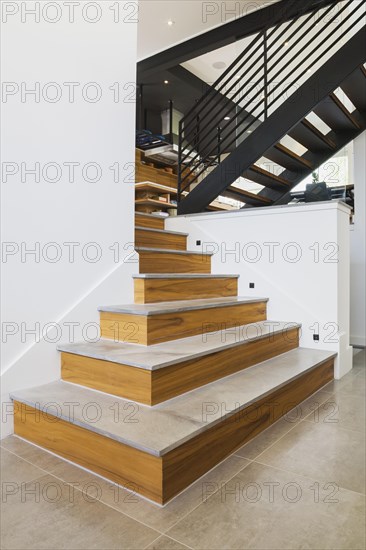 American walnut wood topped with granite and black powder coated cold rolled steel stairs inside a modern cube style home, Quebec, Canada, North America