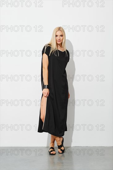 Charming blonde woman in black sleeveless dress and leather sandals