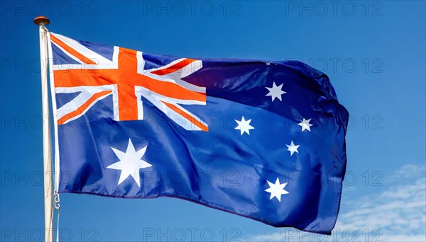 The flag of Australia flutters in the wind, isolated against a blue sky