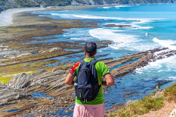 A man with his back turned in Algorri cove on the coast in the flysch of Zumaia, Gipuzkoa. Basque Country