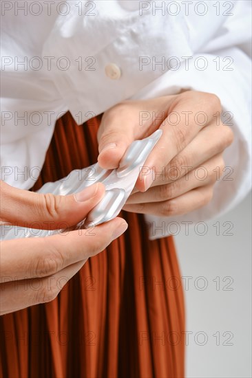 Close up view of fingers squeeze a pill out of the package