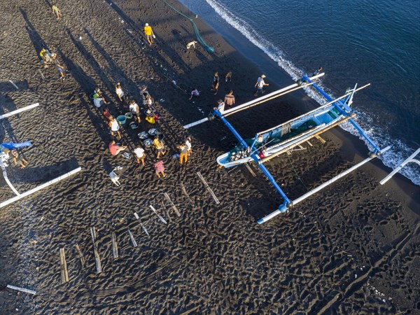 Fishermen unload their catch from their outrigger boat in the morning. Amed, Karangasem, Bali, Indonesia, Asia