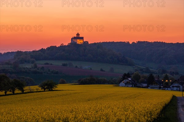 Landscape at sunrise. Beautiful morning landscape with fresh yellow rape fields in spring. Small castle in the yellow fields on a hill. Historic Ronneburg Castle in the middle of nature, Ronneburg, Hesse, Germany, Europe