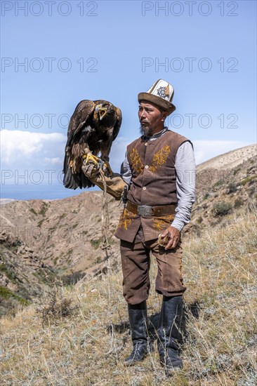 Traditional Kyrgyz eagle hunter with eagle in the mountains, hunting, near Bokonbayevo, Issyk Kul region, Kyrgyzstan, Asia