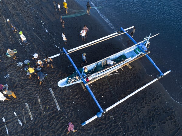 Fishermen unload their catch from their outrigger boat in the morning. Amed, Karangasem, Bali, Indonesia, Asia