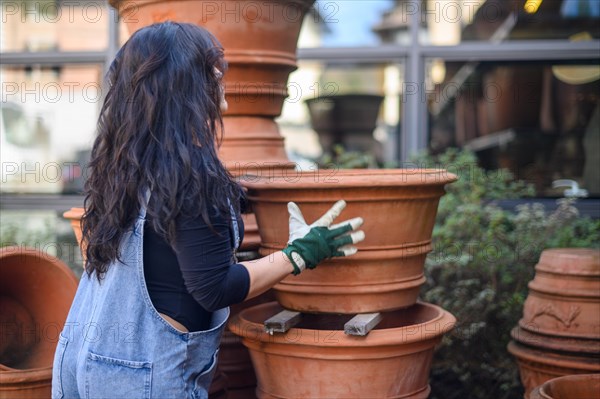 A woman arranging terracotta pots in a workshop setting