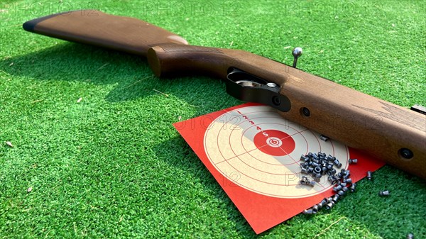 Image of an airsoft gun with pellets and target on a green background