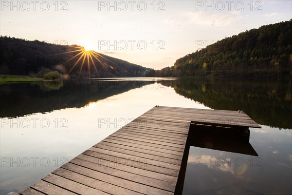 Lake at sunset. Beautiful landscape, taken from the shore of a reservoir. Situated in the middle of the forest and surrounded by nature, the reservoir offers a great atmosphere. Marbach Reservoir, Odenwald, Hesse, Germany, Europe