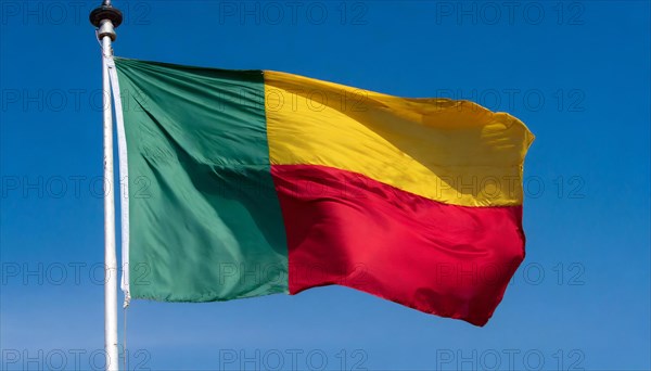 The flag of Benin flutters in the wind, isolated against the blue sky