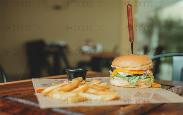 Delicious hamburger with french fries on a wooden table. Cheeseburger with french fries served on wooden table with copy space
