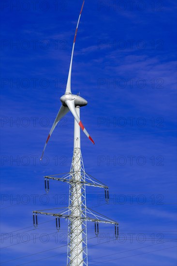 Electricity pylon with high-voltage lines and wind turbine at the Avacon substation Helmstedt, Helmstedt, Lower Saxony, Germany, Europe