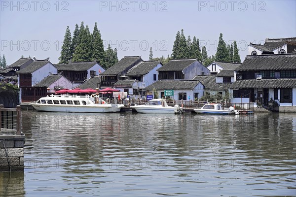 Excursion to Zhujiajiao water village, Shanghai, China, Asia, Wooden boat on canal with view of historical architecture, Traditional houses and boats on a calm river with clear sky in the background, Asia