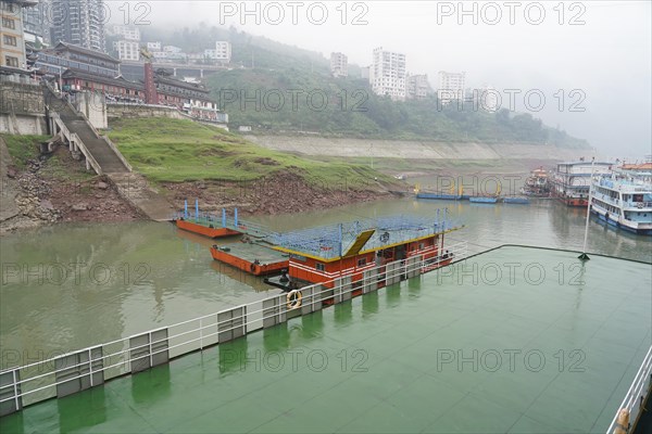 Yichang, Hubei Province, China, Asia, Foggy day with view of ships at a jetty along a river with a city in the background, Shanghai, Asia