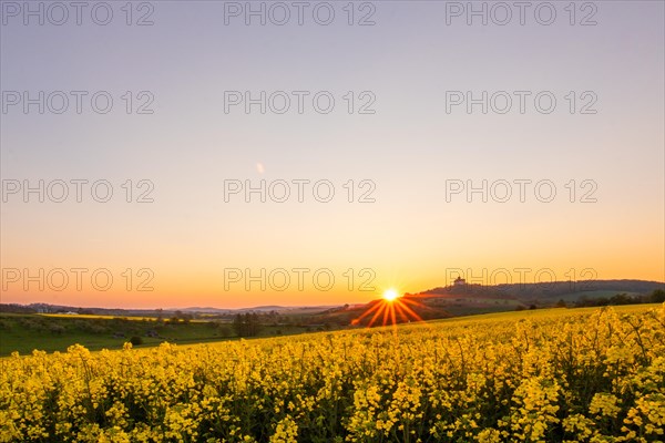 Landscape at sunrise. Beautiful morning landscape with fresh yellow rape fields in spring. Small castle in the yellow fields on a hill. Historic Ronneburg Castle in the middle of nature, Ronneburg, Hesse, Germany, Europe