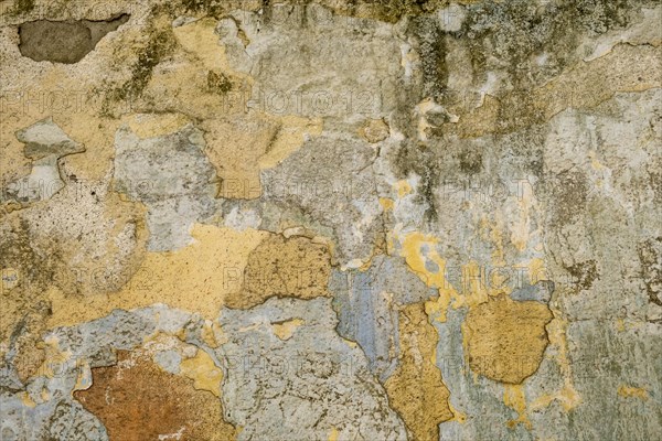 An old wall with peeling paint in various shades of brown, yellow and orange, background, texture