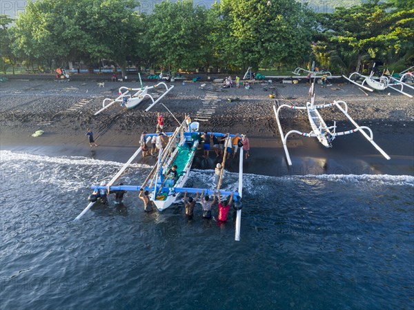 Fishermen unload their catch from their outrigger boat in the morning. Amed, Karangasem, Bali, Indonesia, Asia