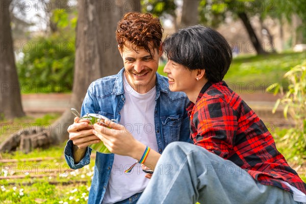 Gay couple enjoying a day in the park sitting together under the sun