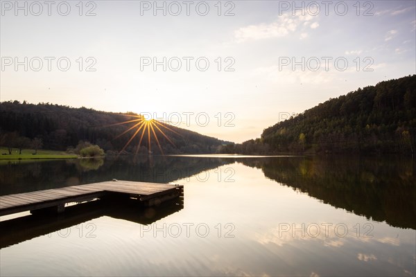 Lake at sunset. Beautiful landscape, taken from the shore of a reservoir. Situated in the middle of the forest and surrounded by nature, the reservoir offers a great atmosphere. Marbach Reservoir, Odenwald, Hesse, Germany, Europe