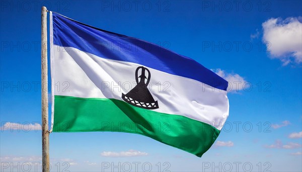 The flag of Lesotho, fluttering in the wind, isolated, against the blue sky