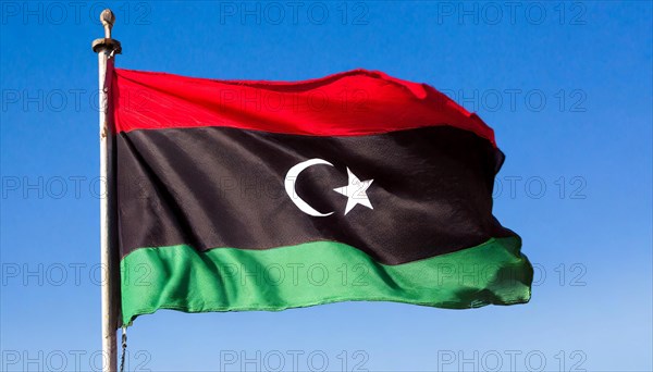 The flag of Libya, fluttering in the wind, isolated, against the blue sky