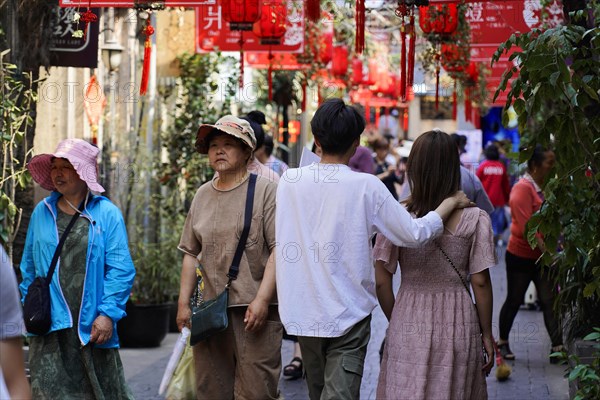 Strolling through the restored Tianzifang neighbourhood, people walking through a shopping street with red banners and urban flair, Shanghai, China, Asia