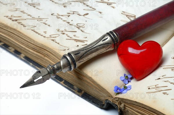 Pen with pen holder and red heart on diary