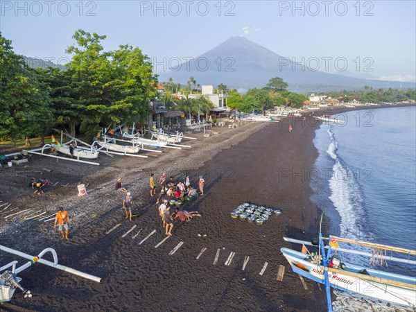 Fishermen unload their catch from their outrigger boat in the morning, in the background Gunung Agung, Amed, Karangasem, Bali, Indonesia, Asia