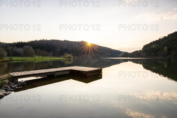 Lake at sunset. Beautiful landscape, taken from the shore of a reservoir. Situated in the middle of the forest and surrounded by nature, the reservoir offers a great atmosphere. Marbach Reservoir, Odenwald, Hesse, Germany, Europe